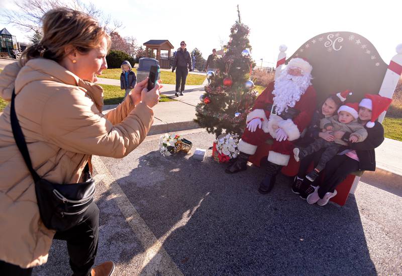 Jill Laughter of Glen Ellyn takes a picture of her children (left-right) Molly, Noah and Grace with Santa while attending the Glen Ellyn Park District's Polar Market held at Maryknoll Park Saturday, Dec. 9, 2023.