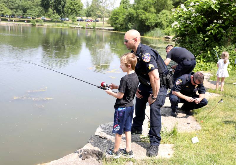 Wheaton Police Sgt. Daniel Salzmann fishes with 7-year-old Axel Anderson during the Wheaton Police Department and DuPage County Forest Preserve Police Cops & Bobbers community fishing event at Herrick Lake Forest Preserve in Wheaton on Wednesday, June 7, 2023.