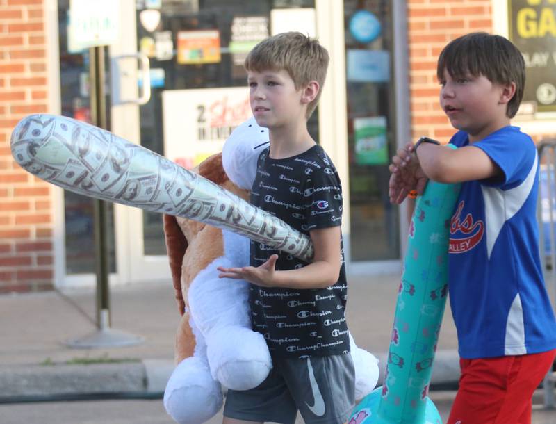 Beni Verucchi and his friend Jaxsen Croissant walk through the carnival with a large stuffed animal and inflatable baseball bats that they won during Spring Valley Summerfest on Thursday, June 19, 2025 downtown Spring Valley. The festival features a carnival, live entertainment, food vendors and fireworks on Saturday at dusk.