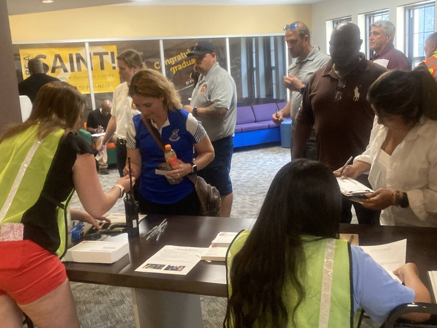 Reunification drill participants representing parents collect their student pick-up forms from Will County Emergency Management Agency employees during an emergency training program for first responders and local school personnel at University of St. Francis in Joliet on Wednesday, July 23, 2025.