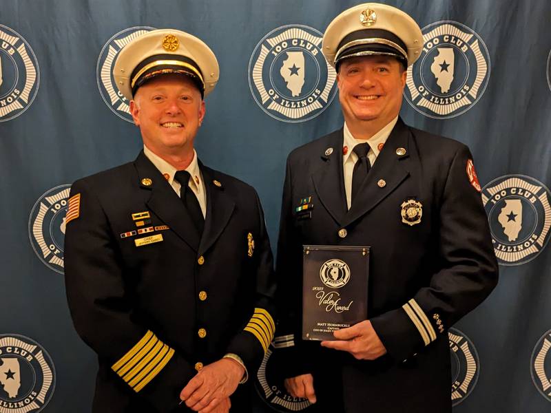 oliet Fire Department Capt. Matt Hornbuckle (right) is joined by Fire Chief Jeff Carey as he displays the Medal of Valow given him by the 100 Club of Illinois for an off-duty rescue in Rockdale.