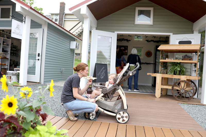 Kourtney Bodnar shares a snack with her niece, Avery Kuhn, 2, during opening day of the Batavia Boardwalk Shops on Friday, May 20, 2022. All businesses are open Fridays, Saturdays, and Sundays through December 18, 2022.
