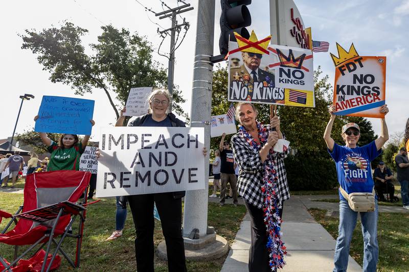 Protestors hold signs criticizing the Trump Administration in Joliet during the No Kings Protest at Mall Loop Drive in Joliet on Oct. 18, 2025.