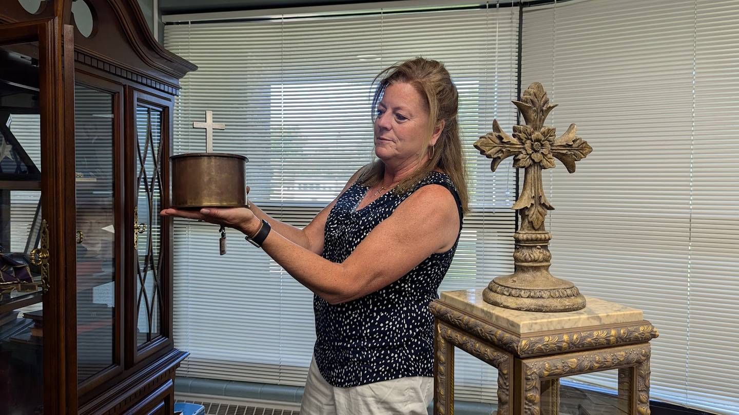 Kim Krumviede, business manager at St. Paul the Apostle Catholic Church in Joliet, holds up an artifact made from a World War II bullet on Wednesday, june 19, 2024, at St. Paul the Apostle Catholic Church in Joliet. The artifact that once belonged to St. Paul's first pastor Rev. Gordon Michels, (deceased), who served in the Navy.