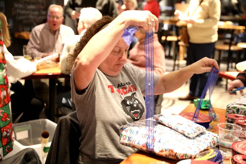 Jeni Wyeth applies a bow to a wrapped gift during a gift wrapping party for clients of the Association for Individual Development (AID) hosted by the Batavia Rotary Club on Thursday, Dec. 12, 2024 at Brother Chimp Brewing in North Aurora.