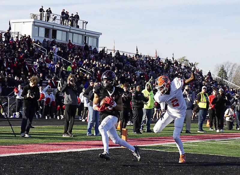Glenbard East's Chris Renford (18) scores a touchdown over Normal's Jackson Eimer (2) during the IHSA Class 7A quarterfinals Saturday November 11, 2023 in Lombard.