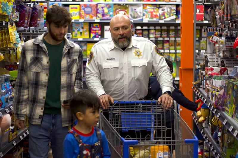Joliet Police Sgt. Tizoc Landeros shops with a child during the 36th annual Santa's Cops event on Saturday, Dec. 6, 2025, at Walmart, 401 Illinois Route 59, in  Shorewood.