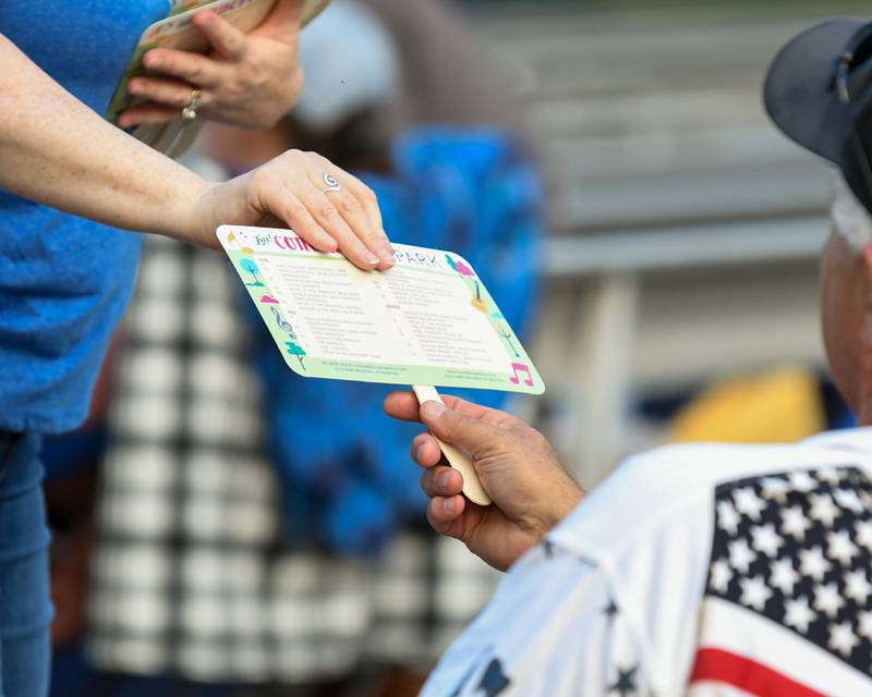 Hand-held fans were passed out to keep attendees cool during the annual Independence Day concert and fireworks show at Hopkins Park in DeKalb on Monday July 4, 2022.