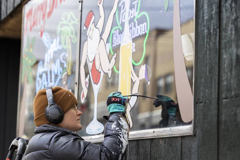 Nora Reuter jazzes up a business window with a holiday themed motif Wednesday, Nov. 20, 2024, in downtown Dixon.