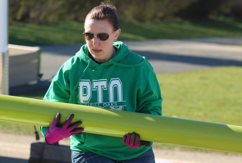 Three Oaks Elementary School PTO President Stephanie Steiner helps as volunteers and friends of Three Oaks Elementary School constructed a new playground at the Cary school on Saturday.