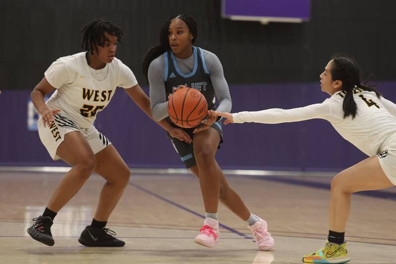 Joliet Catholic’s Layla Pierce drives through Joliet West’s Mariah Shelton (25) and Christina Keoborakot (4) in the WJOL Basketball Tournament at Joliet Junior College Event Center on Monday