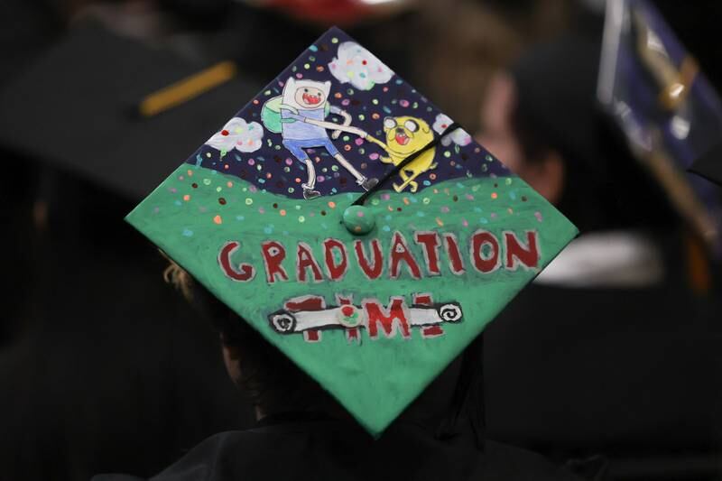 A graduate customizes their hat with characters from the show Adventure Time at the Joliet Junior College Commencement Ceremony on Friday, May 19, 2023, in Joliet.