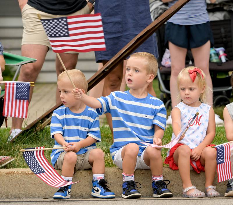 Micah, Luca and Mila Guido of Winfield wave American Flags while watching the annual Wheaton Independence Day Parade on Thursday, July 4, 2024.