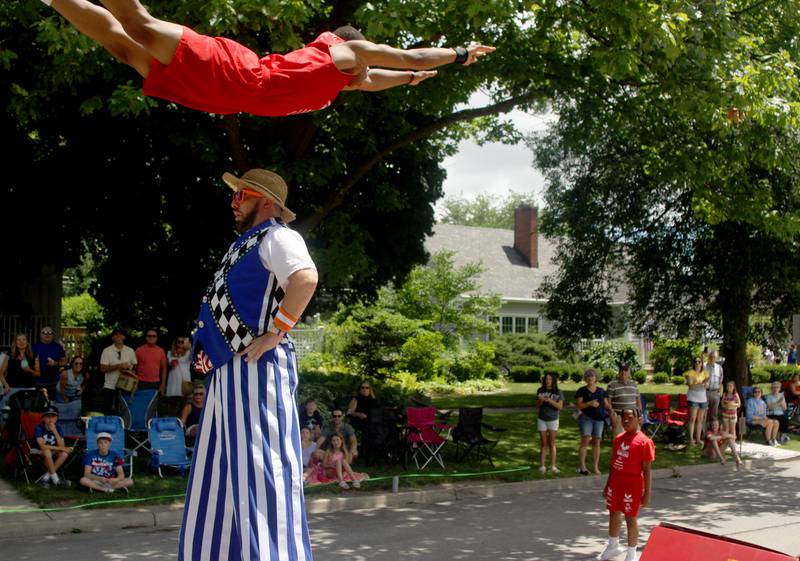 Stilt walker Jason Kollum of Niles poses as a Jesse White tumbler soars over him during the Swedish Days parade along Anderson Boulevard in Geneva Sunday.