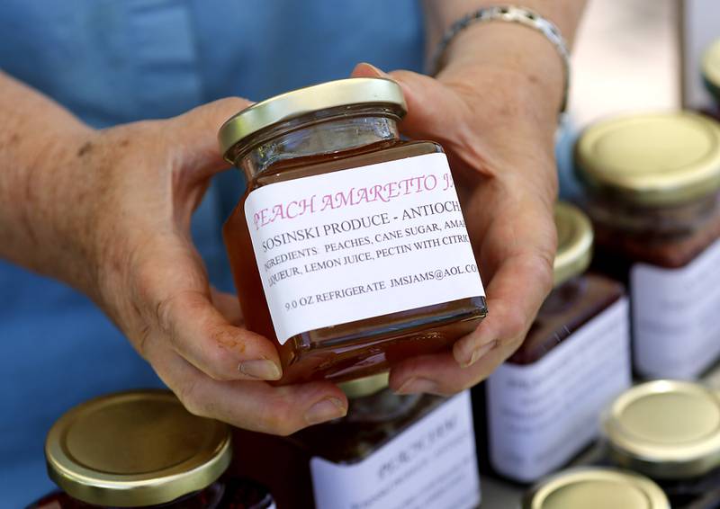 Jan Sosinski holds up a jar of her jam that she sells from the Sosinski’s Produce booth on Tuesday, June 20, 2023, at a Summer Woodstock Farmers Market around the Historic Woodstock Square. People were able to shop from over 40 of their favorite farms & producers for in-season food fresh produce, dairy, meats, breads, baked goods, spices, herbs, pasta, flowers and more.