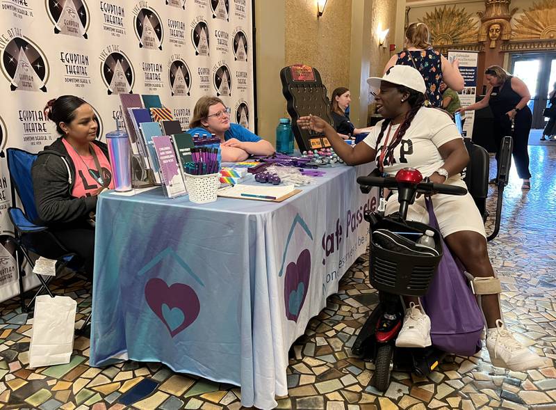 (From left) Sandy Morales, 27, and Shayna Smith, 25, both with Safe Passage talk with Shamyra William, 34, at RAMP's resource fair in the Egyptian Theatre in DeKalb on July 26, 2023.