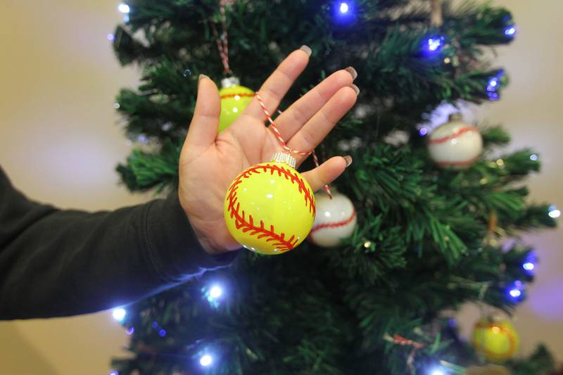 Felicia Salazar, of Round Lake shows one of the handmade softball ornaments that will hang on the Avon Township Youth Baseball & Softball tree which will be on display in the Giving Trees exhibit at the Grayslake Heritage Center & Museum.