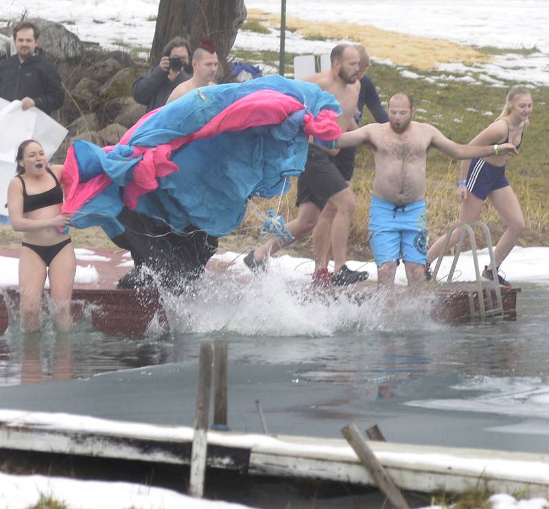 The Skycicles team from Skydive Chicago uses a parachute as they jump into he icy waters Saturday, Jan. 27, 2024, at the swimming pond at Skydive Chicago in Ottawa during the annual Penguin Plunge. The event raised money for the Make-A-Wish Foundation.