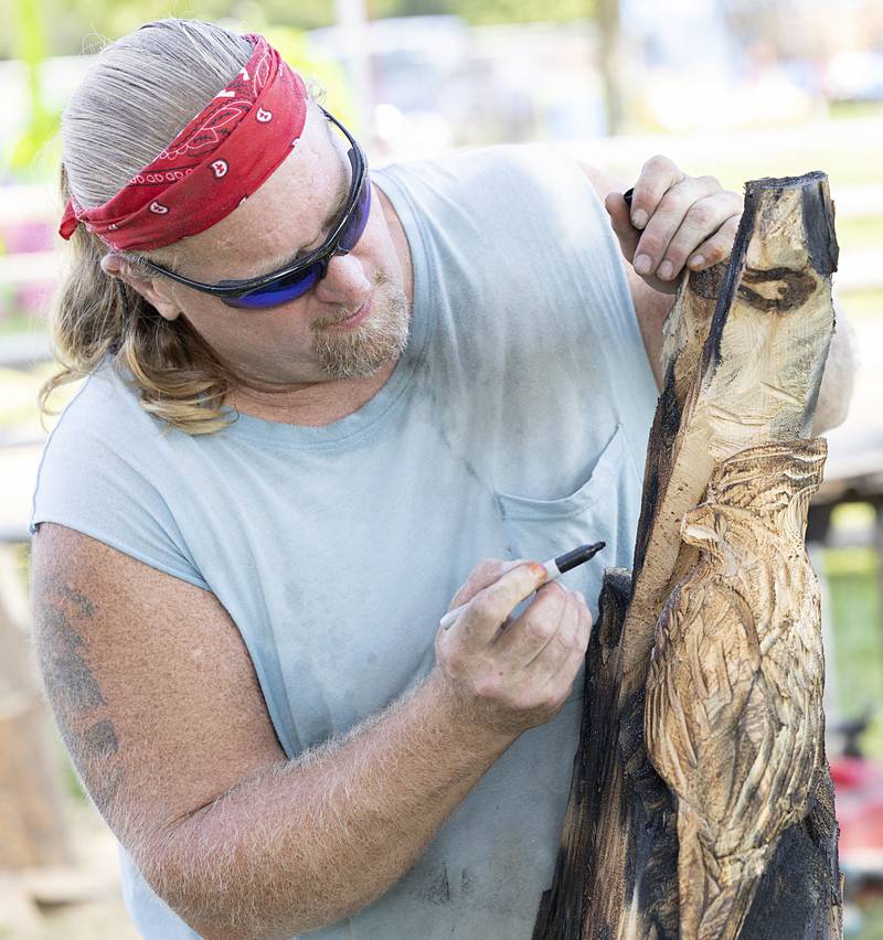 Wood carver Bruce Rose maps out his sculpture Wednesday, July 31, 2024 at the Ogle County Fair. This piece will be part of a bench that will go to the silent auction on Saturday.