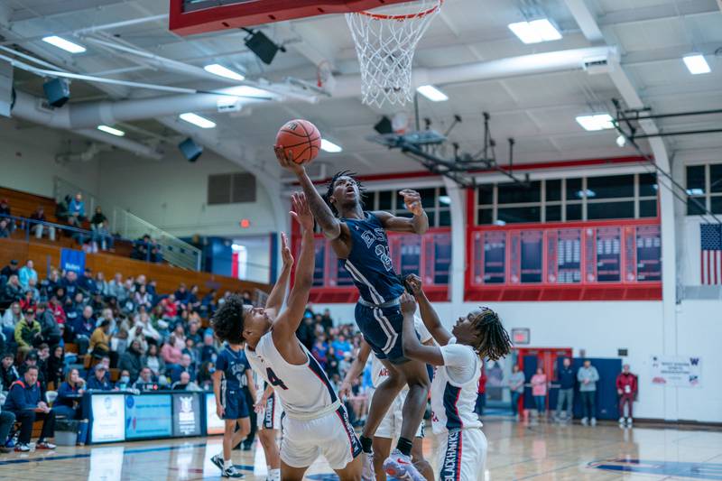 Oswego East's Mekhi Lowery (24) drives to the basket against West Aurora's Joshua Pickett (4) and Denta'e Woods (1) during a basketball game at West Aurora High School on Friday, Jan 27, 2023.