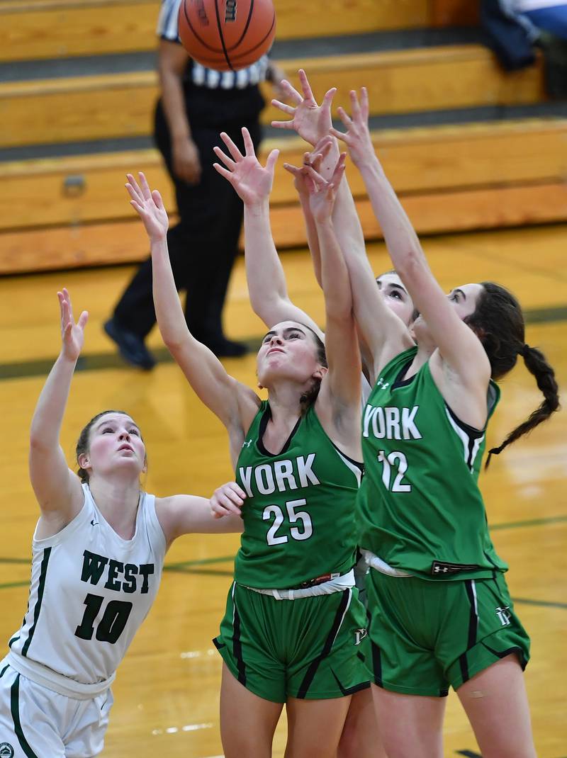 Glenbard West's Julia Benjamin (10) and York's Michaela Quinn (25) and Ellie Kehoe (12) reach for a rebound during a game on Jan. 22, 2024 at Glenbard West High School in Glen Ellyn.