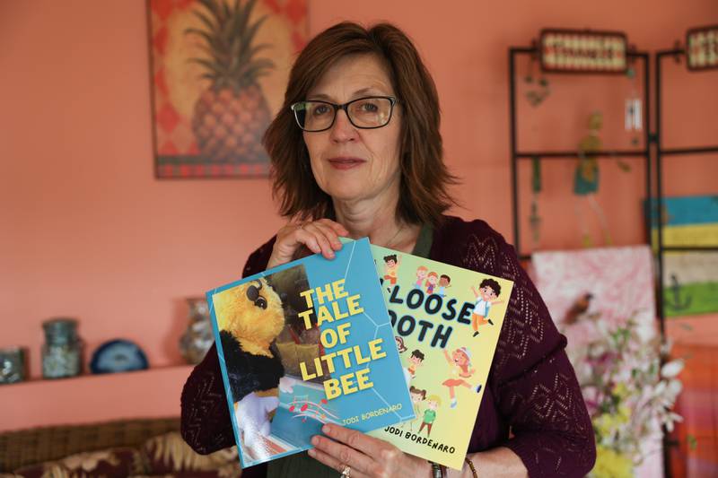 Jodie Bordenero poses for a photo with her two published books, including one of a bee puppet on Tuesday, June 27th, 2023 in Lockport.