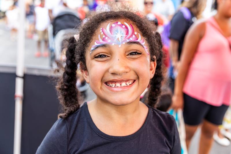 Maya Pina-Pruitte (8) shares a smile after getting her face painted by Audra Measner at Kidz Fest in Joliet on Aug. 3, 2024.