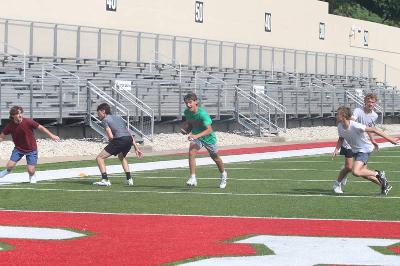 L-P's Noah Zebron (center) runs the football during a drill during their football camp at Howard Fellows Stadium on Tuesday, July 25, 2023 in Peru.