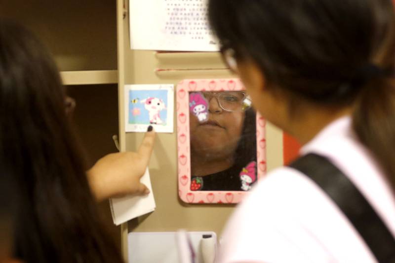 Jazmin Vargus, 10, is reflected in her mirror as she puts items in her locker at Duker Elementary School in McHenry, on Tuesday, Aug. 15, 2023, during school supplies drop-off day.