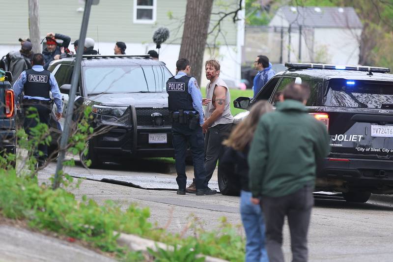 Two actors converse by a police car along the 500 block of North Bluff street between filming on Monday, April 27, 2026 in Joliet. HBO began filming the pilot for “American Blue” that follows a police chief retuning to Joliet to take over the police department.