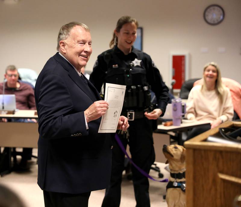 Batavia Mayor Jeffery Schielke holds up the certificate, with a paw print signature, for River, the Batavia Police Department’s new 11-month-old comfort dog, on Monday, April 21, 2025 during a Batavia City Council meeting.