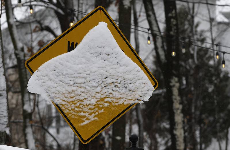 Snow covers a warning sign on Broadway Street on Friday,  Dec. 9, 2022, in Richmond. Areas of McHenry County received a couple of inches on snow after a winter storm moved through the county.