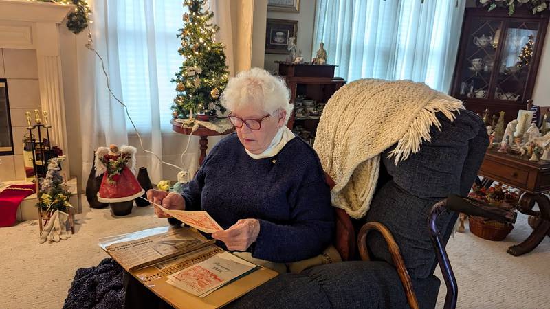 Elvira Balog, 85, of Joliet, looks through memorabilia from the 25th anniversary of the former St. Stephen Catholic Church in Joliet on Monday, December 16, 2024. Balog watched original St. Stephen's Hungarian Chapel burn to ground on Dec. 31, 1948.