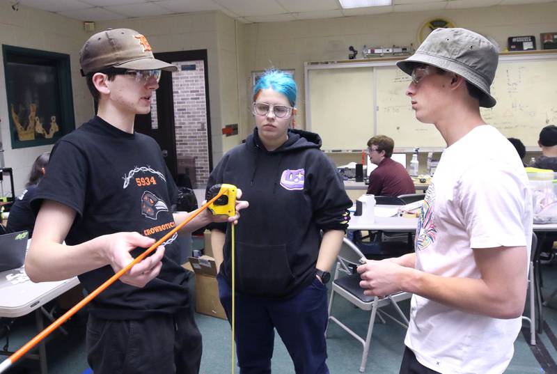Blake Bollow, (left) a senior at DeKalb High School, Abby Slater, also a senior, and Nathan Tumminaro, a junior, discuss some measurements during a Crowbotics team meeting Tuesday, April 10, 2024, at Huntley Middle School in DeKalb. Crowbotics is DeKalb High School’s robotics team who has qualified to compete in the FIRST Robotics Competition World Championship held in Houston, Texas April 17-20.