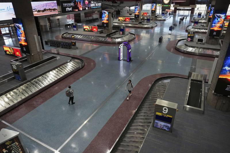 People walk through Harry Reid International Airport, Friday, Aug. 29, 2025, in Las Vegas. (AP Photo/John Locher)