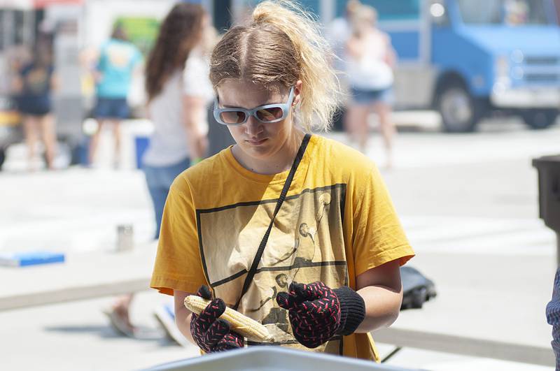 Geneva Connelly, 16, shucks corn during Shuckfest in Morrison. The Saturday, July 30, 2022 festival is the first of its kind for the town.