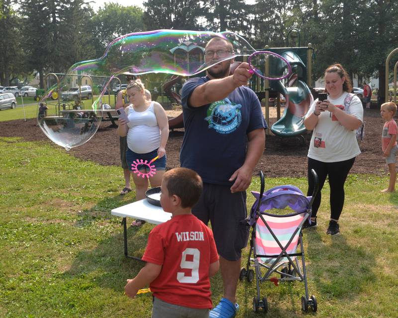 Justin Wilson of German Valley uses a wand to make a big bubble as his son, Kash, watches during Jason Kollum's "Big Bubble Time' event at Ben Miller Park during German Valley Days on Saturday, July 15, 2023.