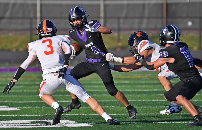 Downers Grove North’s Caden Chiarelli (4) tries to escape two Lincoln-Way West tacklers during a Class 7A quarterfinal game on November 15, 2025 at Downers Grove North High School in Downers Grove .
