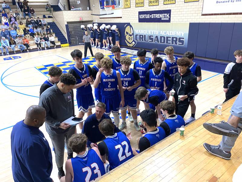 Marmion Academy boys basketball coach Joe Piekarz (kneeling at center) talks things over with his Cadets during a timeout Tuesday, Jan. 7, 2025, at Bader Gym in Ottawa.