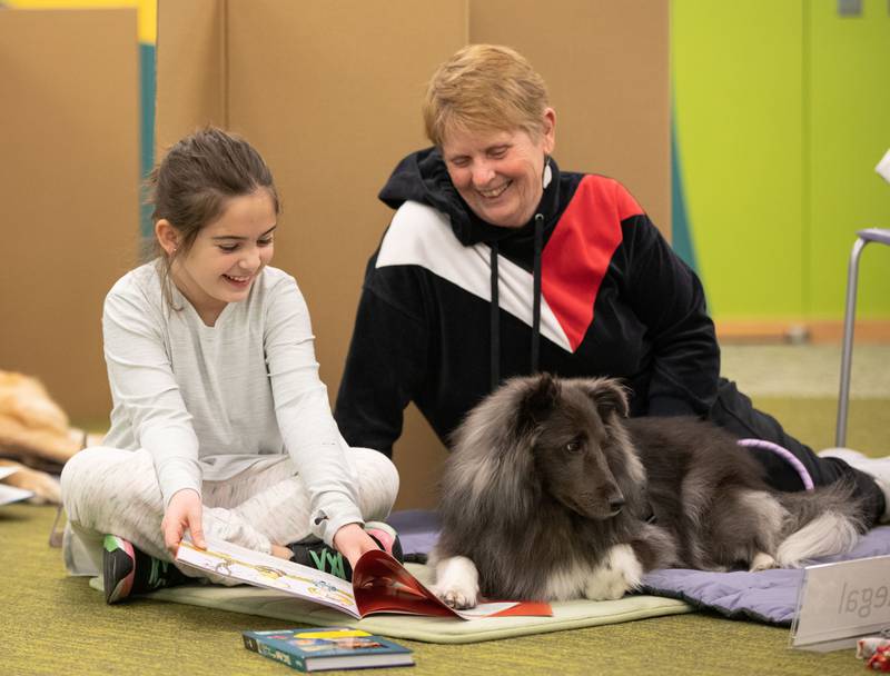 Lillian, 8, (left) reads to therapy dog Regal at the Elmhurst Public Library on Saturday, Feb. 12, 2023.