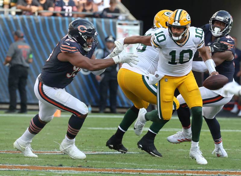 Green Bay Packers quarterback Jordan Love escapes the pressure of Chicago Bears defensive end DeMarcus Walker during their game Sunday, Sept. 10, 2023, at Soldier Field in Chicago.