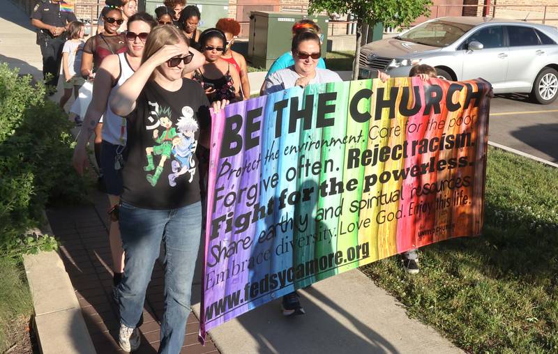 Participants march down the sidewalk on East Locust Street Thursday, June 23, 2022, during a parade to celebrate Pride month in DeKalb. The function included a short parade through downtown and a showing of the movie “Tangerine,” with a panel discussion afterwards at the Egyptian Theatre.