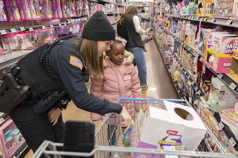 Dixon Police Officer Cassandra Dempsey looks over items with Brianna on Saturday, Dec. 13, 2025, for the annual Shop with a Cop shopping spree.