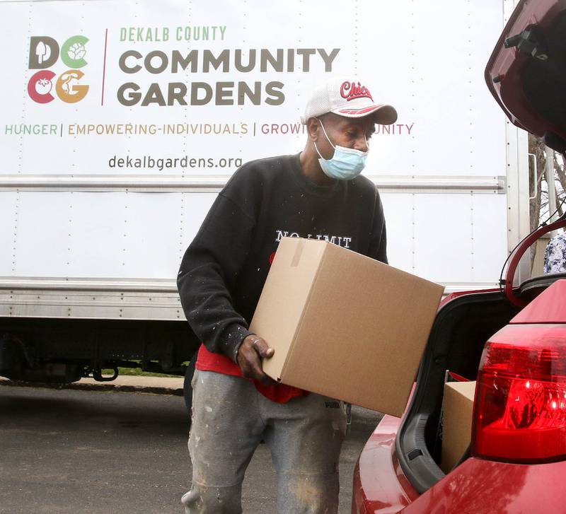File photo: Kevin Green with DeKalb County Community Gardens carries a box of food to a car in April 2021 at Suburban Apartments in DeKalb during a food distribution by DCCG at the complex.