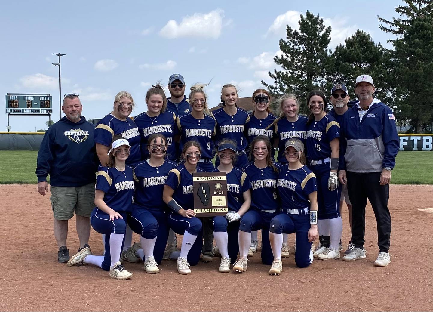 The Marquette Academy softball team poses with its freshly won regional title plaque in front of the scoreboard in Grant Park on Saturday, May 20, 2023.
