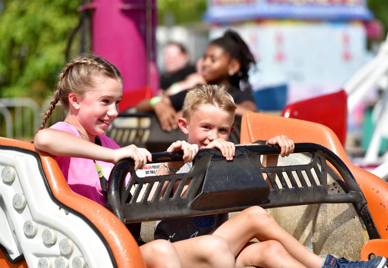 Mason Szoke, 7, and his sister Isabel, 11, of Elgin, ride the Sizzler at the Kane County Fair in St. Charles on Friday, July 14, 2023.