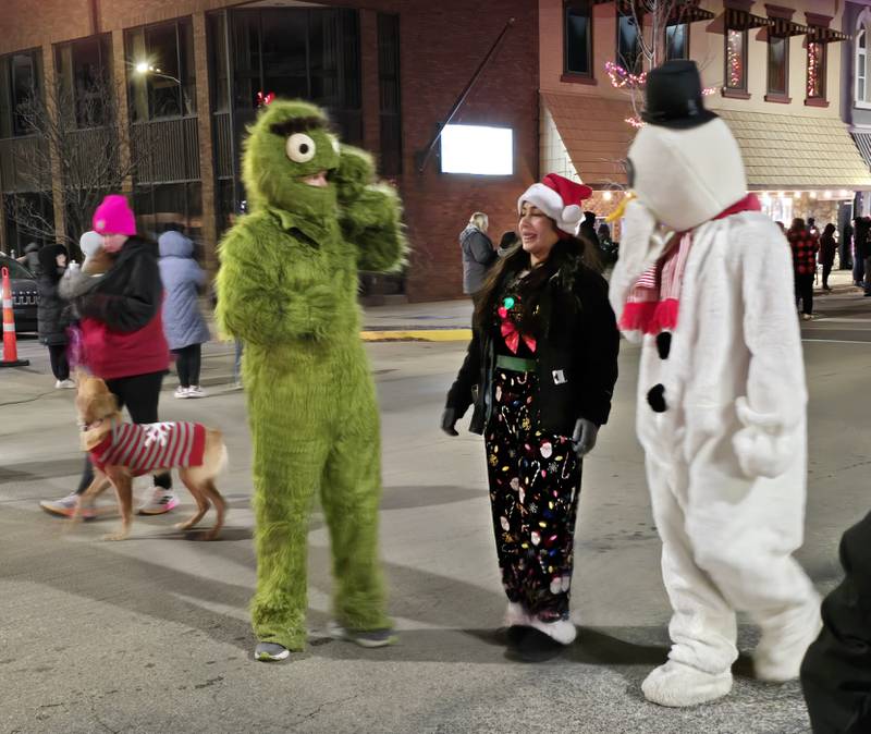 Oscar the Grouch (sans his garbage can) and.a snowman character walk together Saturday, Nov. 30, 2024, during the Lighted Christmas Parade in downtown Streator. The Streator High School Key Club wore the character suits from the Ace Hardware Christmas parades that predated the city's lighted parades.