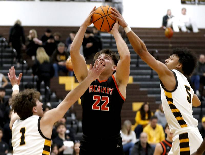 Jacobs' Jordan O'connor (right) blocks the shot of McHenry's Conner McLean (center) as he drives to the basket against Jacobs' Ben Jurzak (left) during a Fox Valley Conference basketball game on Friday, Jan. 24, 2025, at Jacobs' High School.