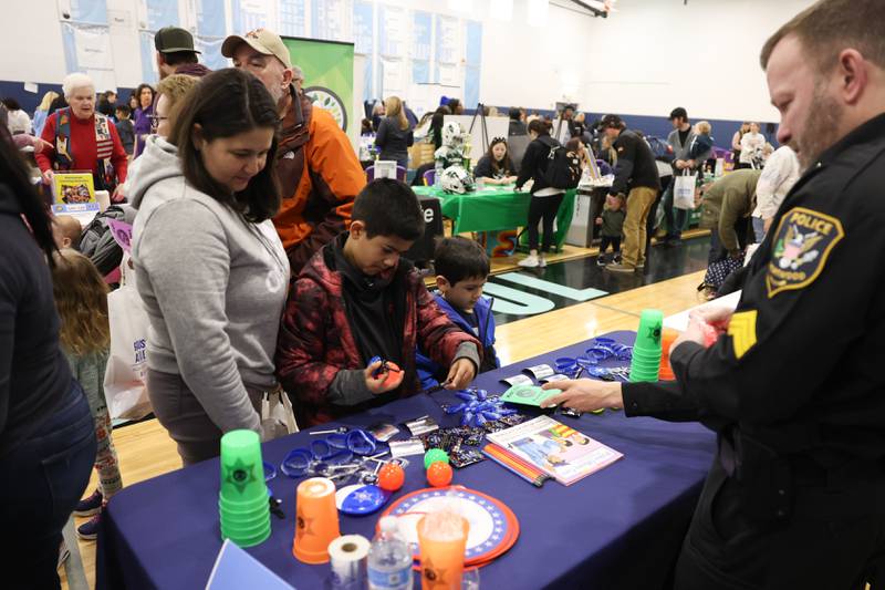 Maria Rubio stands with her sons Carlos, 8, and Ethan, 5, as they pick out items at the Shorewood Police Department vendor at the Will County Executive 2024 Kids’ Fair at Troy Middle School in Plainfield on Monday, Feb. 19, 2024.