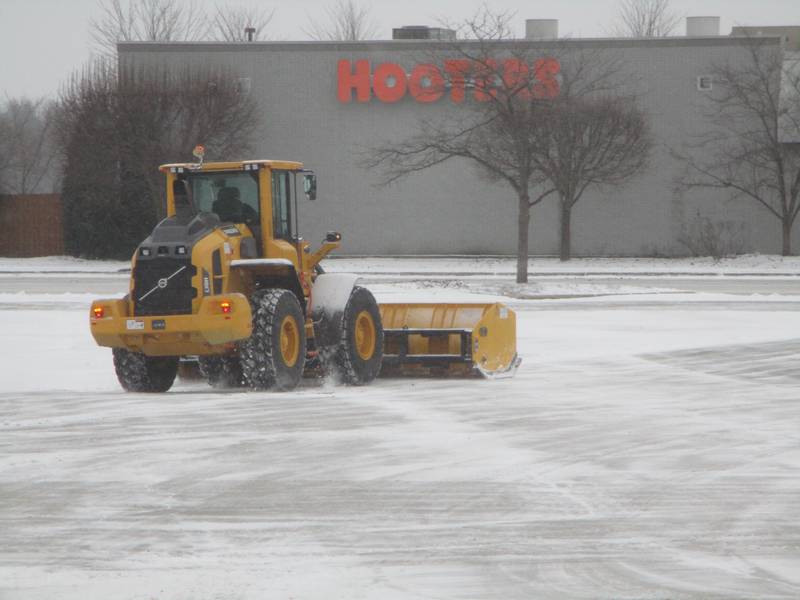 A plow clears snow Wednesday in a parking lot at the Louis Joliet Mall in Joliet with the Hooters restaurant in the background. Feb. 12, 2025.